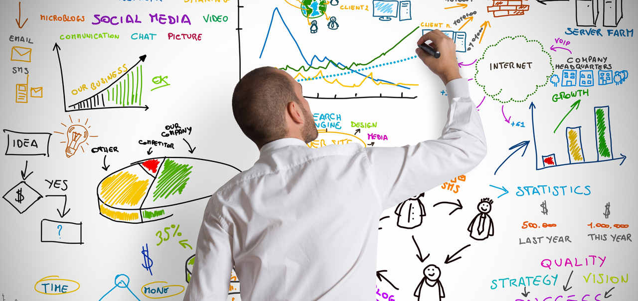 Image of man drawing on a whiteboard that is filled with charts, graphs and illustrations