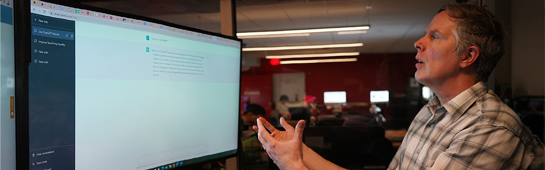 A man indicates to a computer screen with an AI application running
