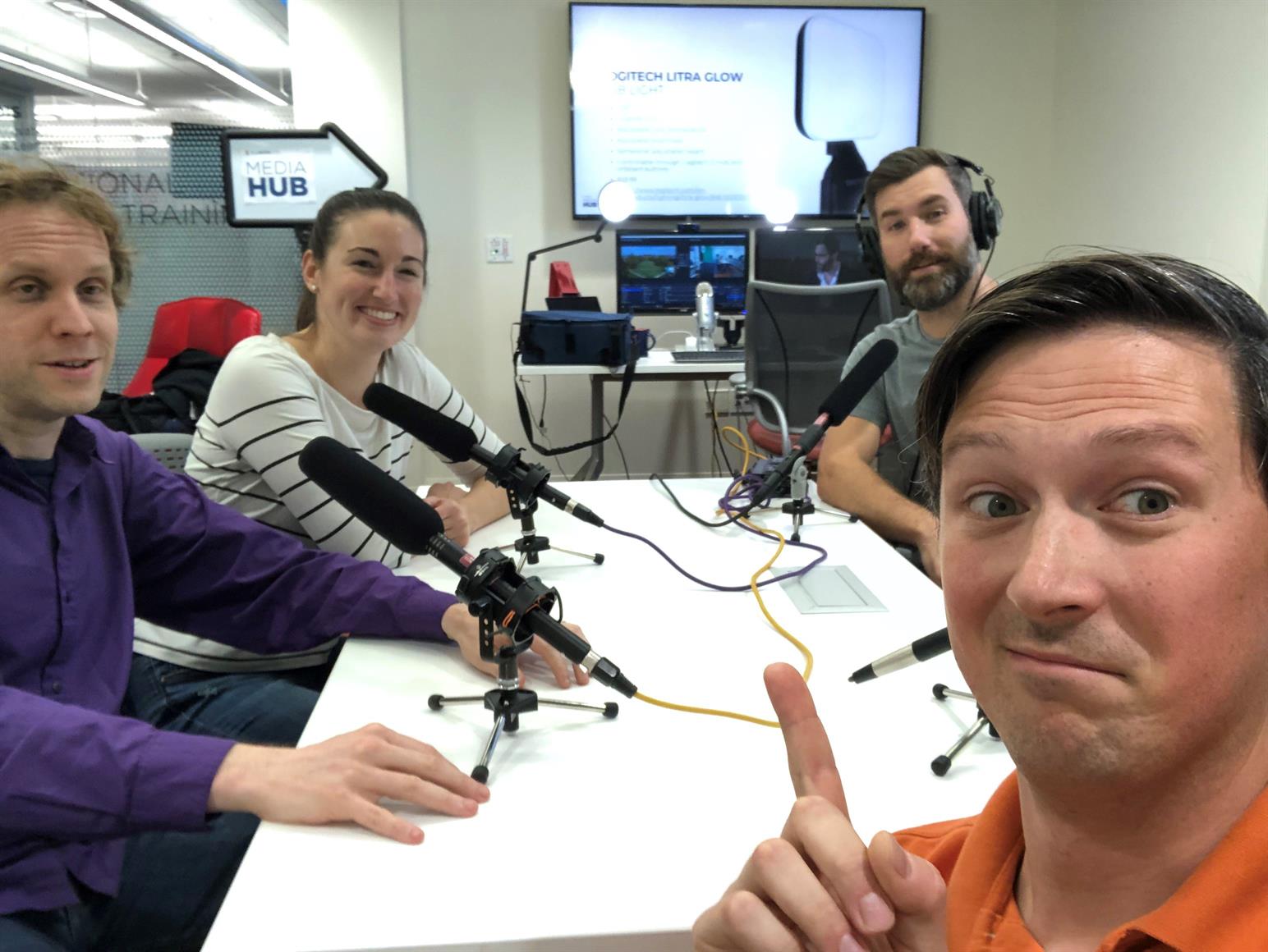 Selfie picture of 4 people around table with microphones.
