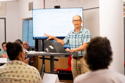 man giving presentation pointing at TV