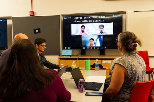 People at a table talking to people over Zoom