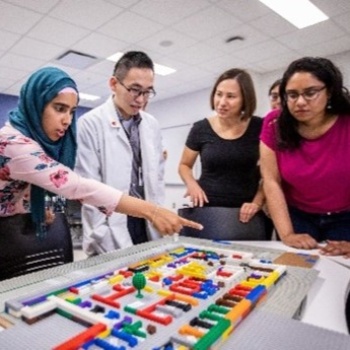 students gathered around a desk looking at objects on the desk