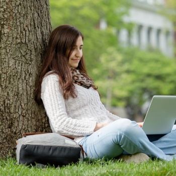 International student on computer on the quad