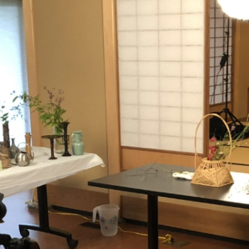 A woman in traditional japanese attire attends to a tea set while a film crew records her