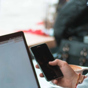 person-looking-at-their-phone-and-laptop