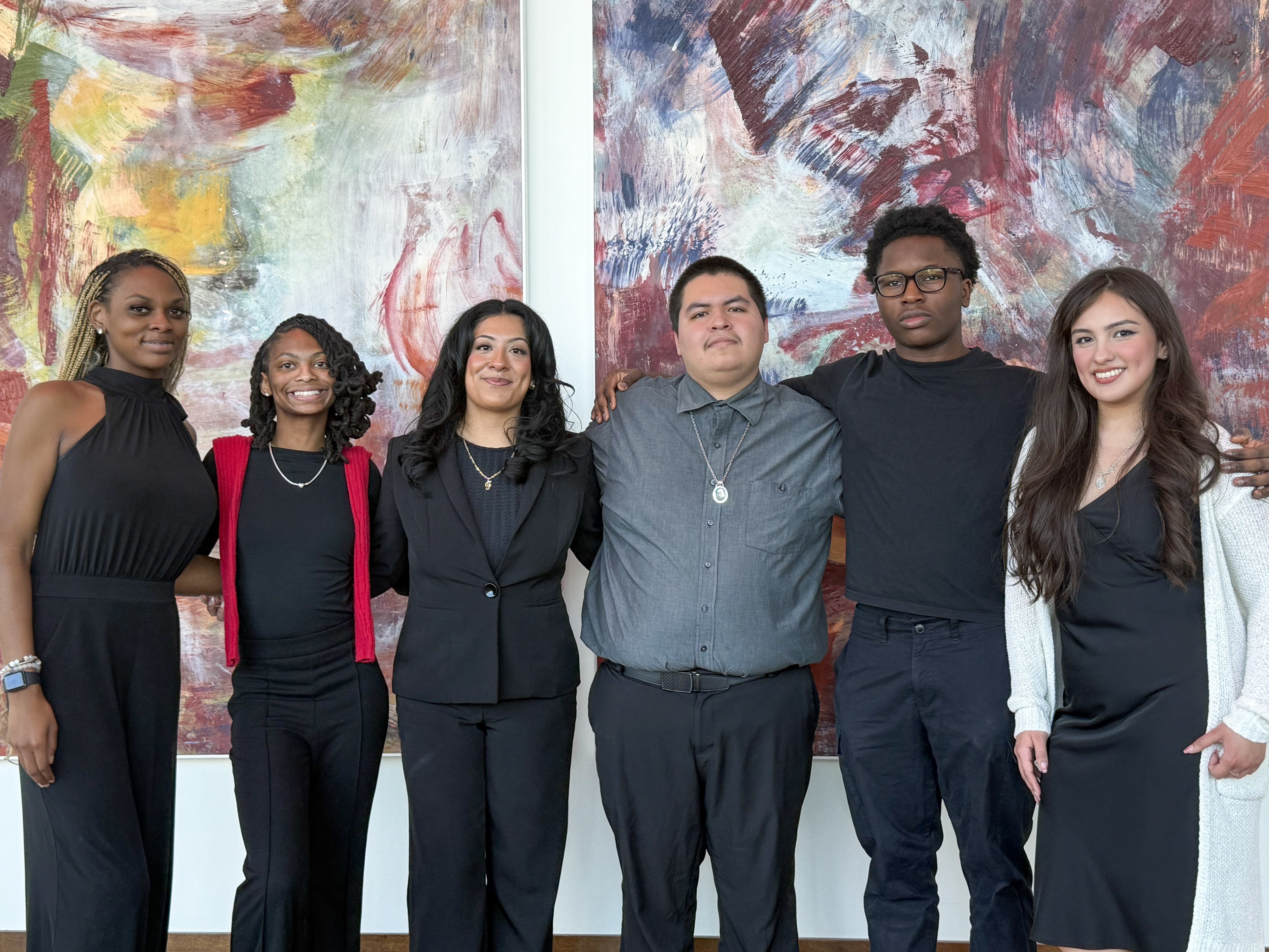 A Group of Attendees at the Annual Black & Latinx 2026 Summit posed in front of large abstract paintings