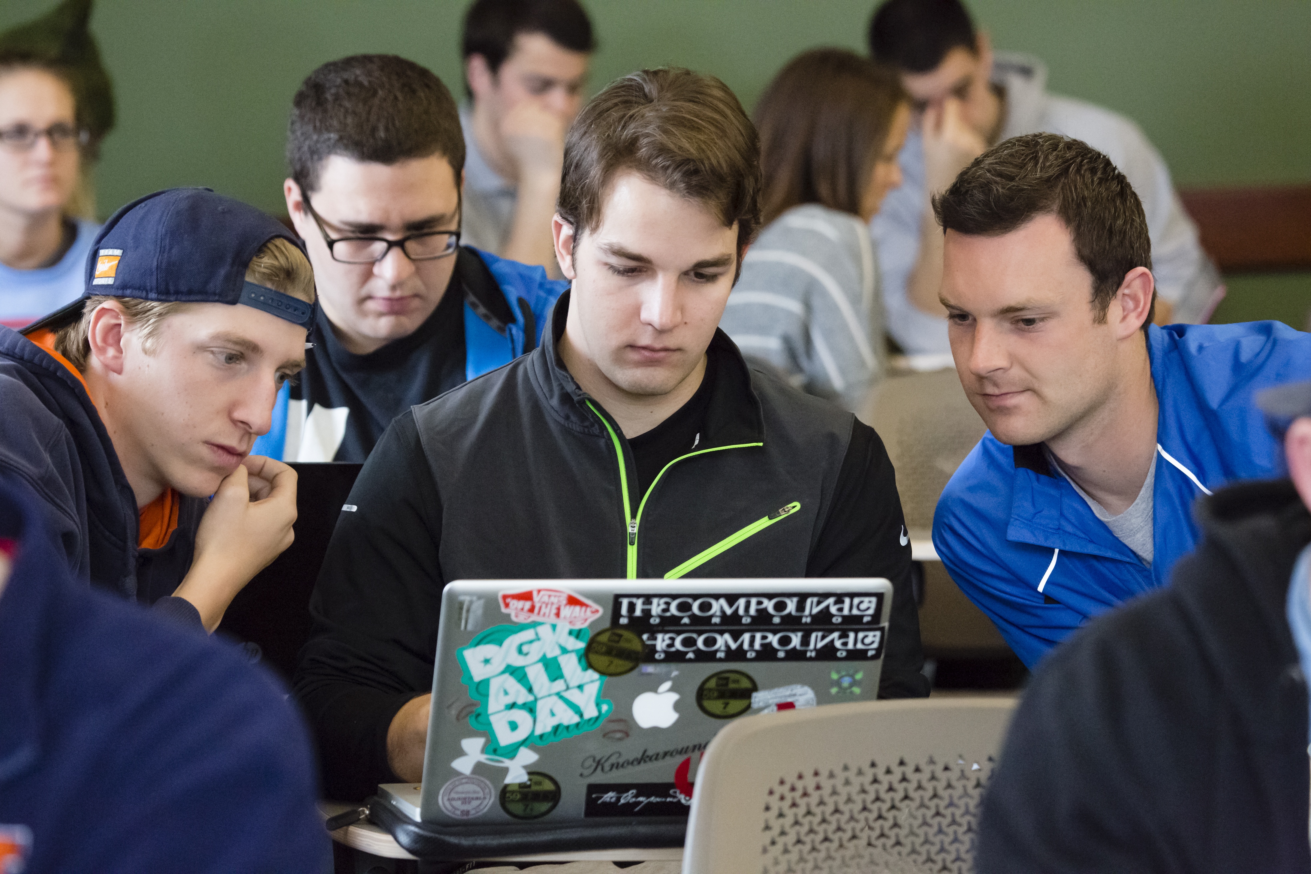 group of students, gathered around a laptop