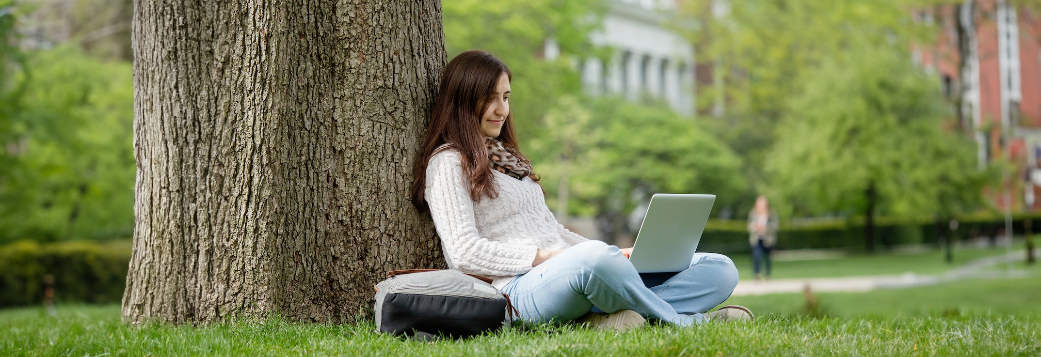 International student on computer on the quad