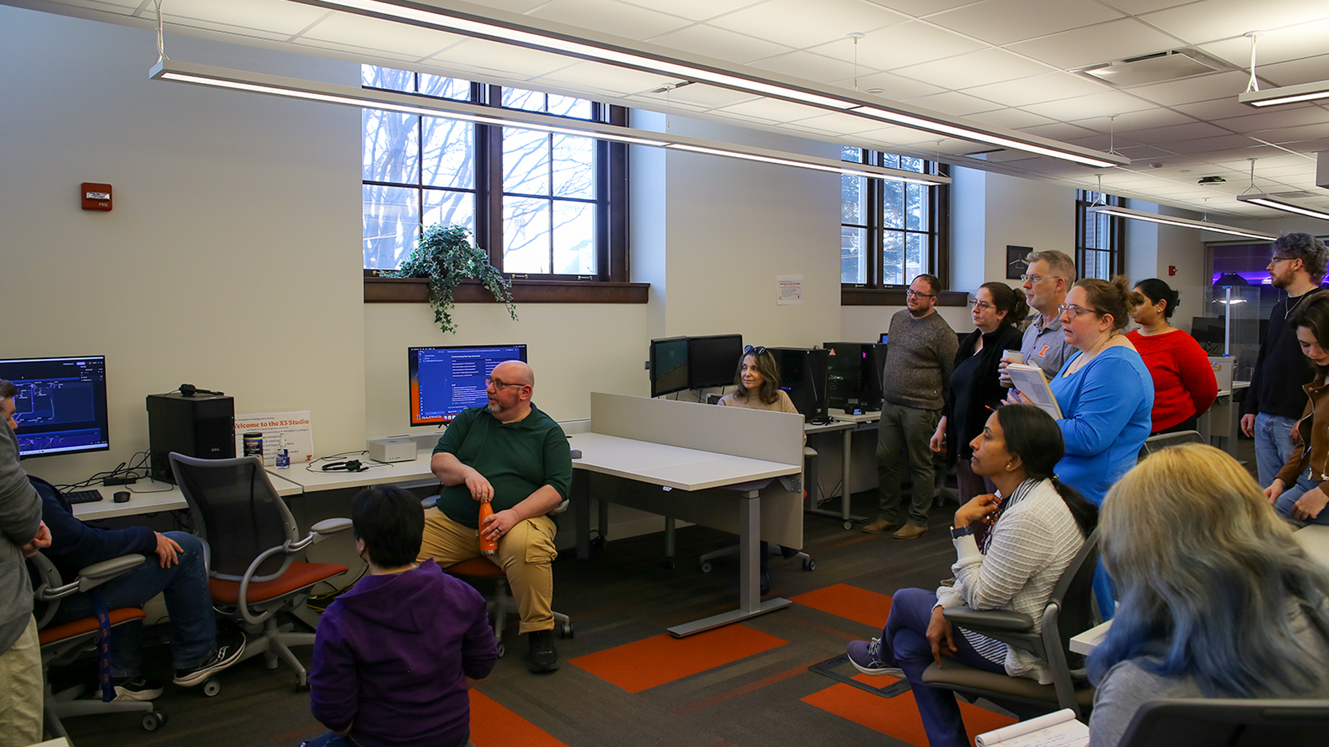 Photo of podcast guests sitting around a table with microphones in X3 Studio