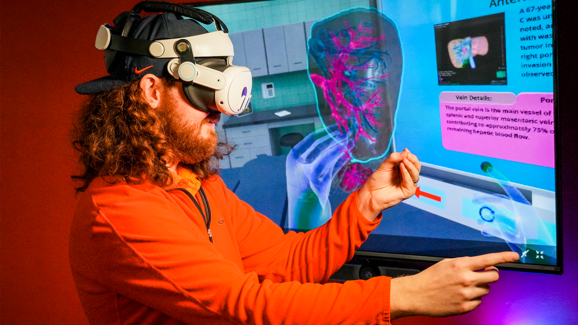 Photo of VR Developer demonstrating Liver Surgery VR app on a TV screen while wearing a VR headset